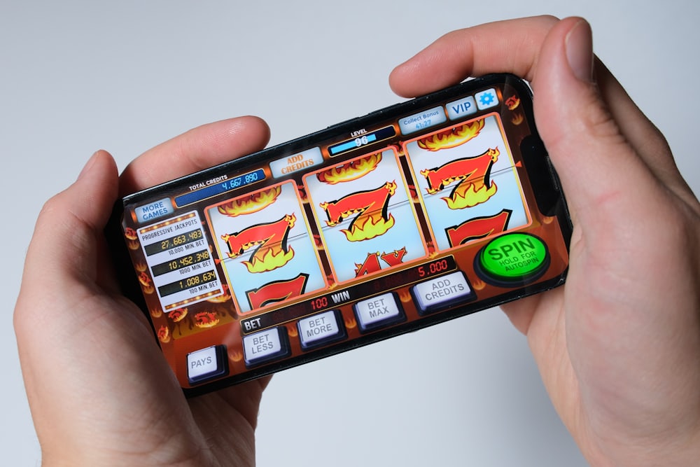 Tangan memegang ponsel dengan tampilan permainan slot