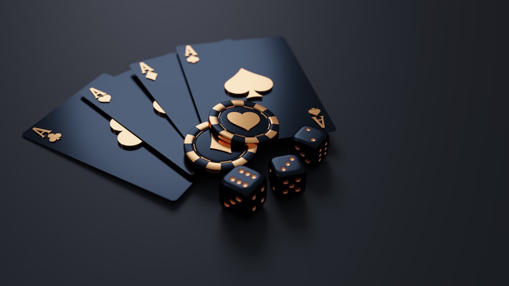 Kartu remi hitam, chip poker emas, dan dadu di atas meja gelap
